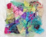 Many colors of irregularly shaped fabric scraps stitched to white background